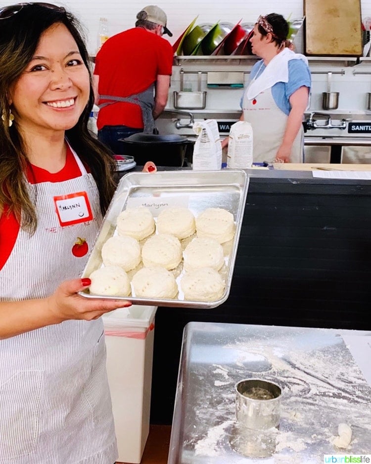 Marlynn Jayme Schotland holding a tray of biscuits in a cooking class in Atlanta.