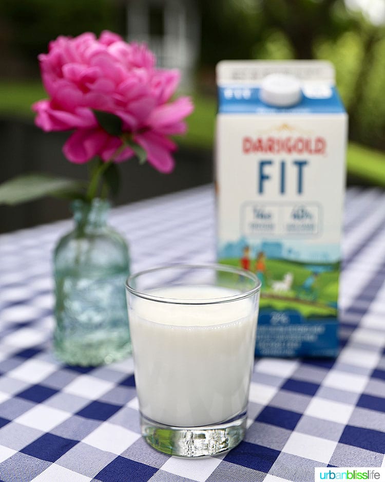ultra-filtered milk in a glass with a milk carton and flowers behind it