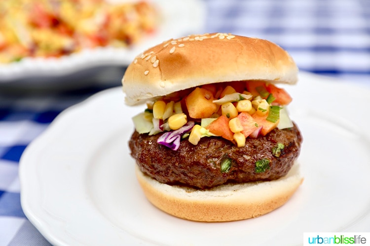 Asian beef burger with bun and corn and cabbage slaw.