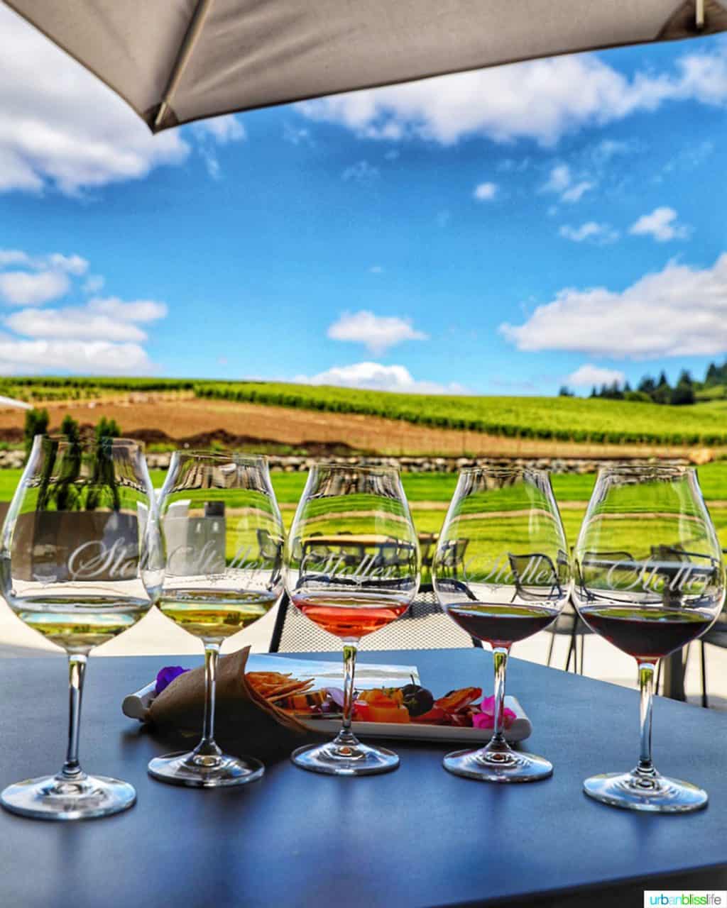 wine flight against a backdrop of vineyards at Stoller