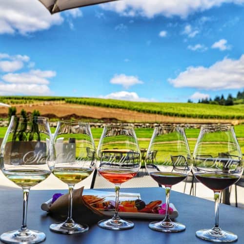 wine flight against a backdrop of vineyards at Stoller