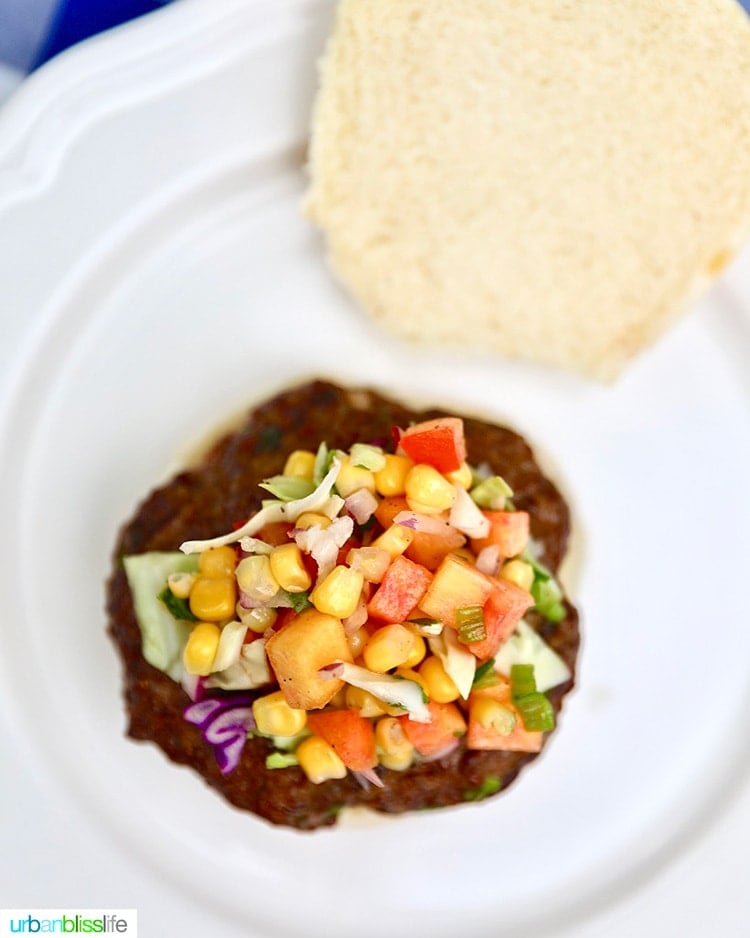 Asian burger overhead topped with corn and peaches slaw.