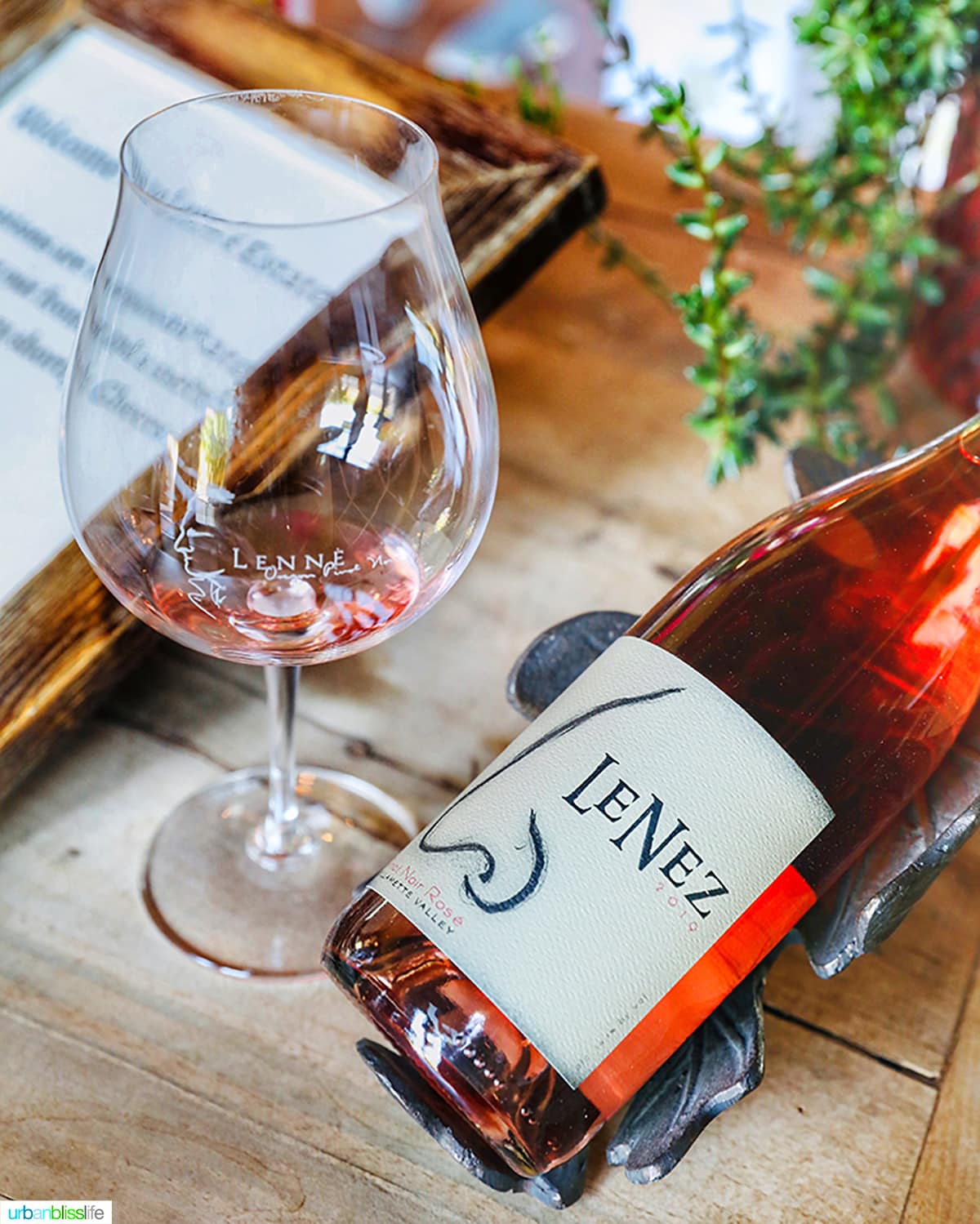 bottle of Lenné Estate rosé with a glass of rosé on a wood table.