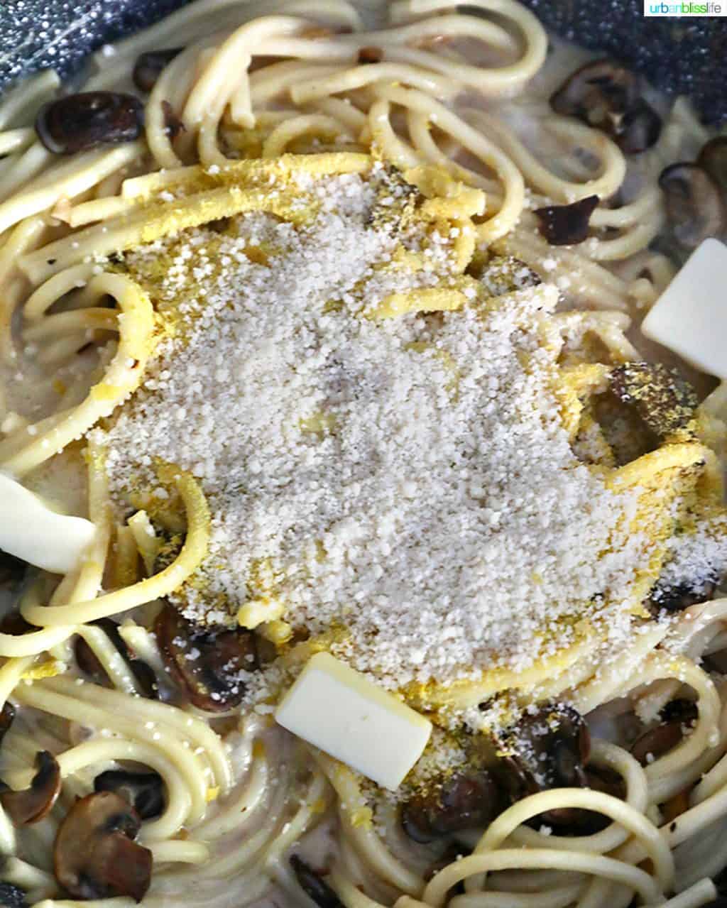 adding parmesan to pasta and mushrooms