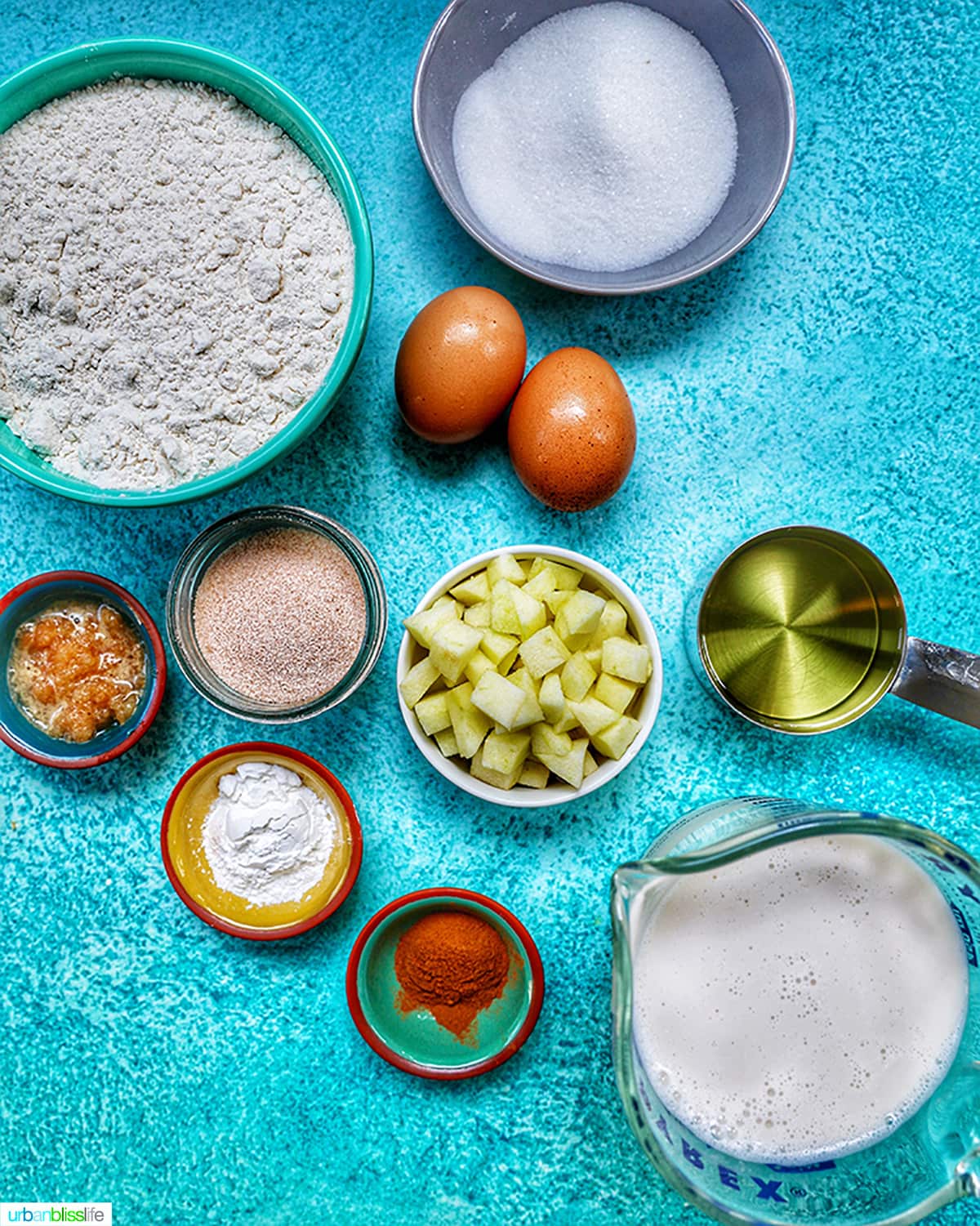 ingredients to make apple cinnamon pancakes on a blue table.