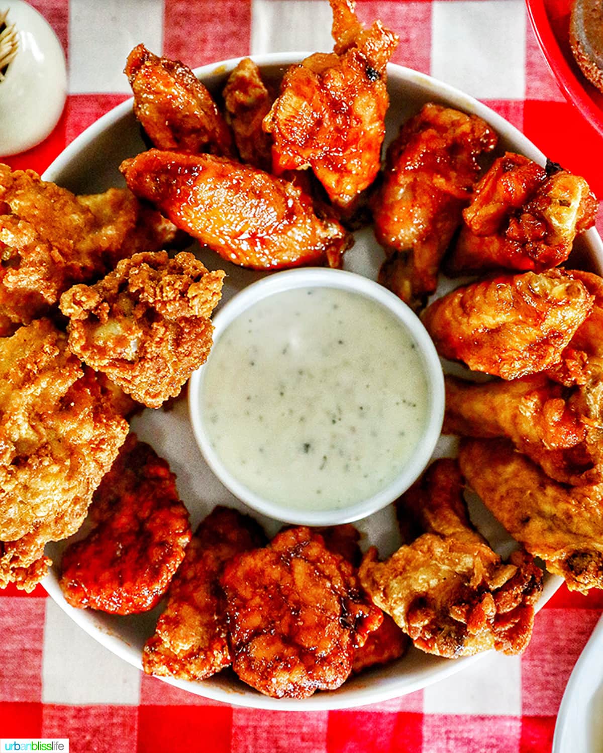 wings and dipping sauce against red and white checkered tablecloth