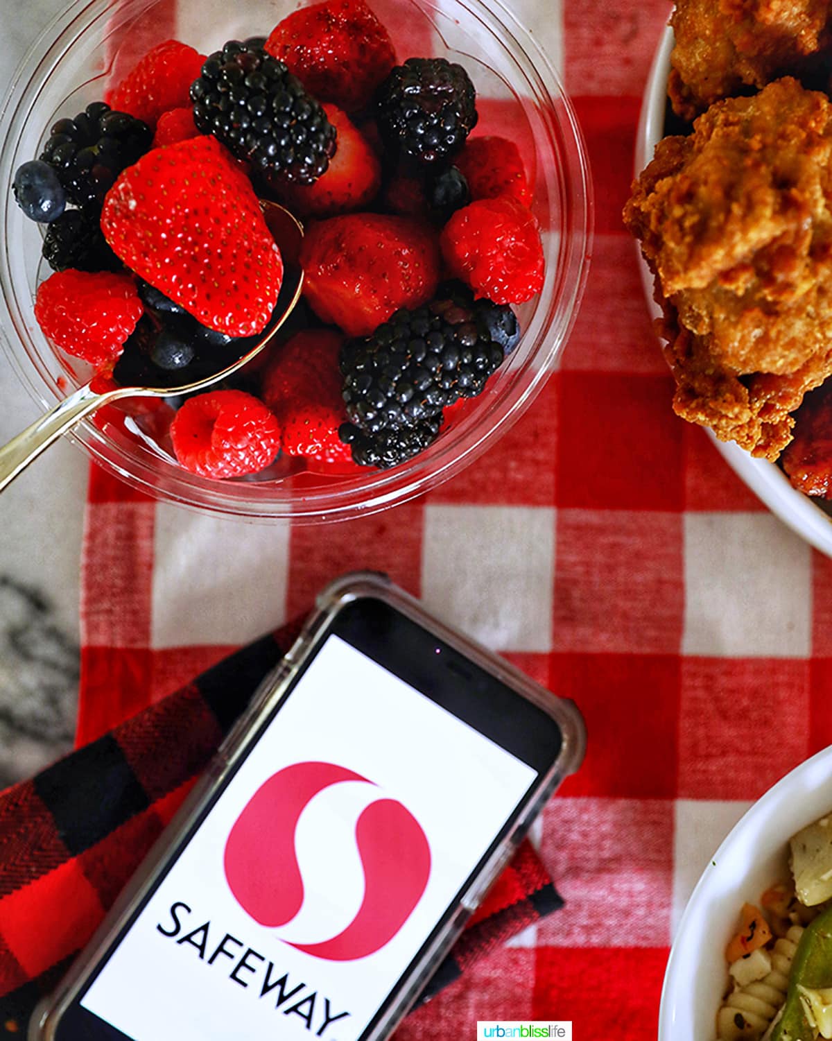 bowl of fruit with safeway logo on phone against red and white checkered tablecloth