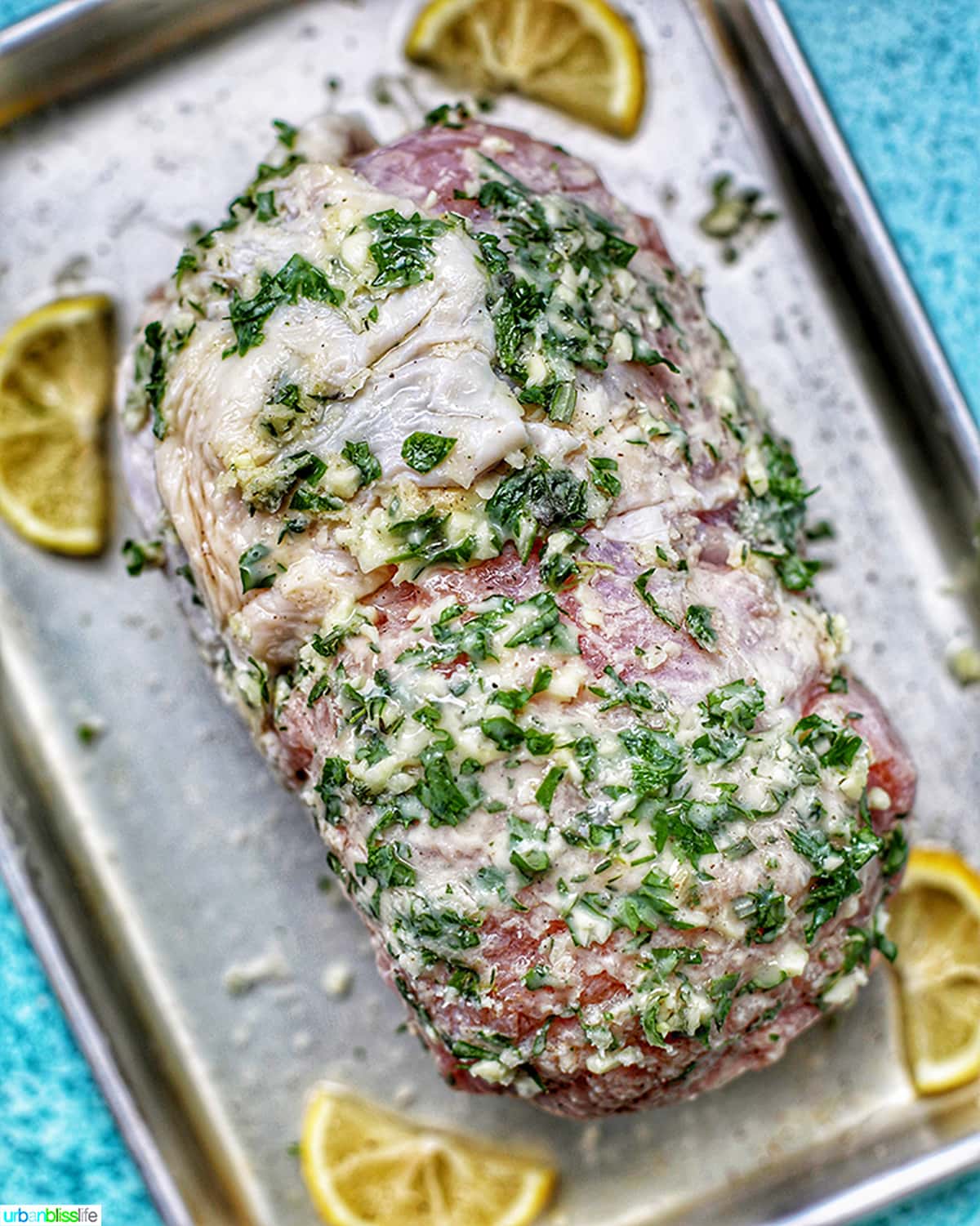 turkey breast with butter and herbs on a sheet tray ready to bake.