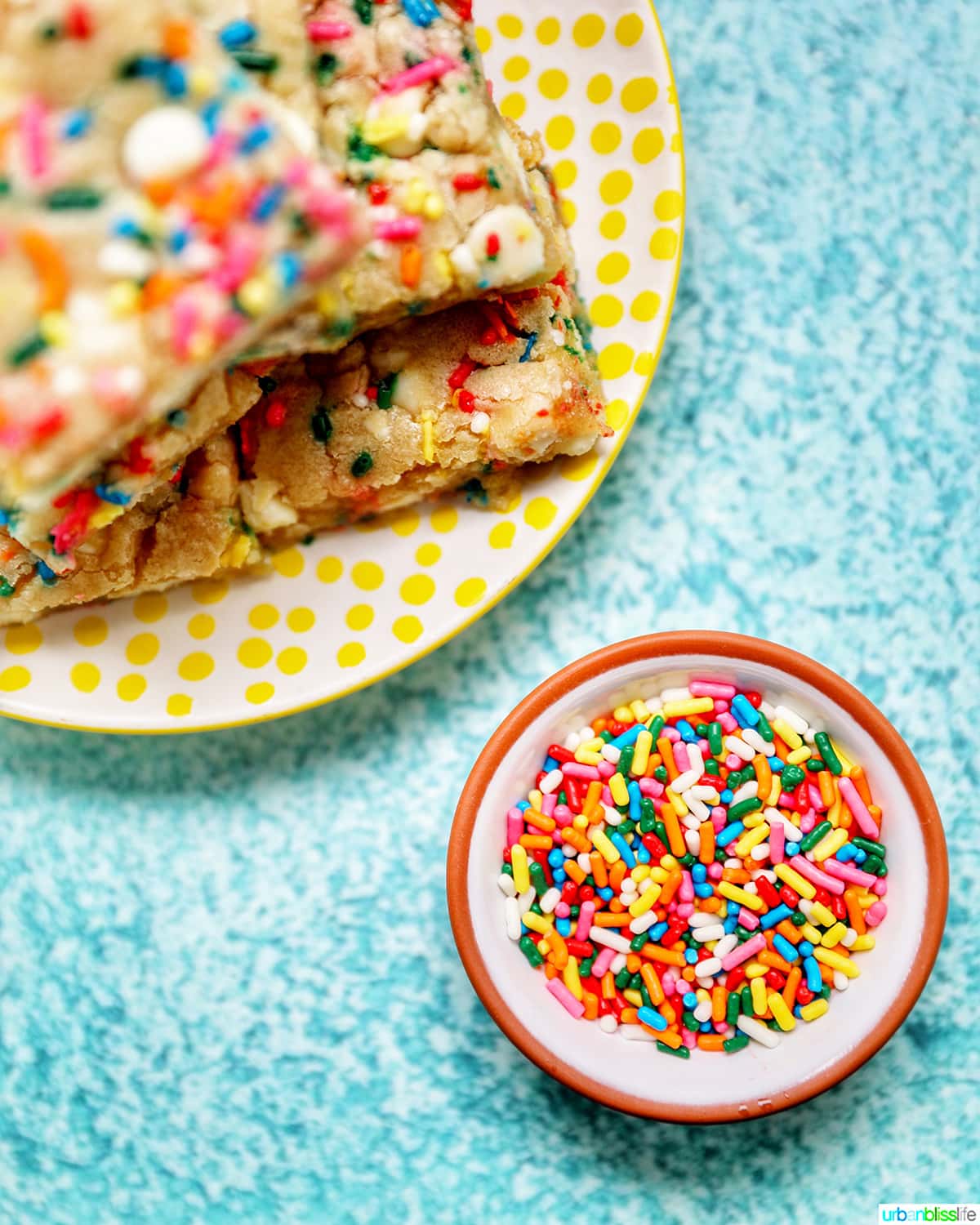 Funfetti Bars on a yellow plate with bowl of sprinkles