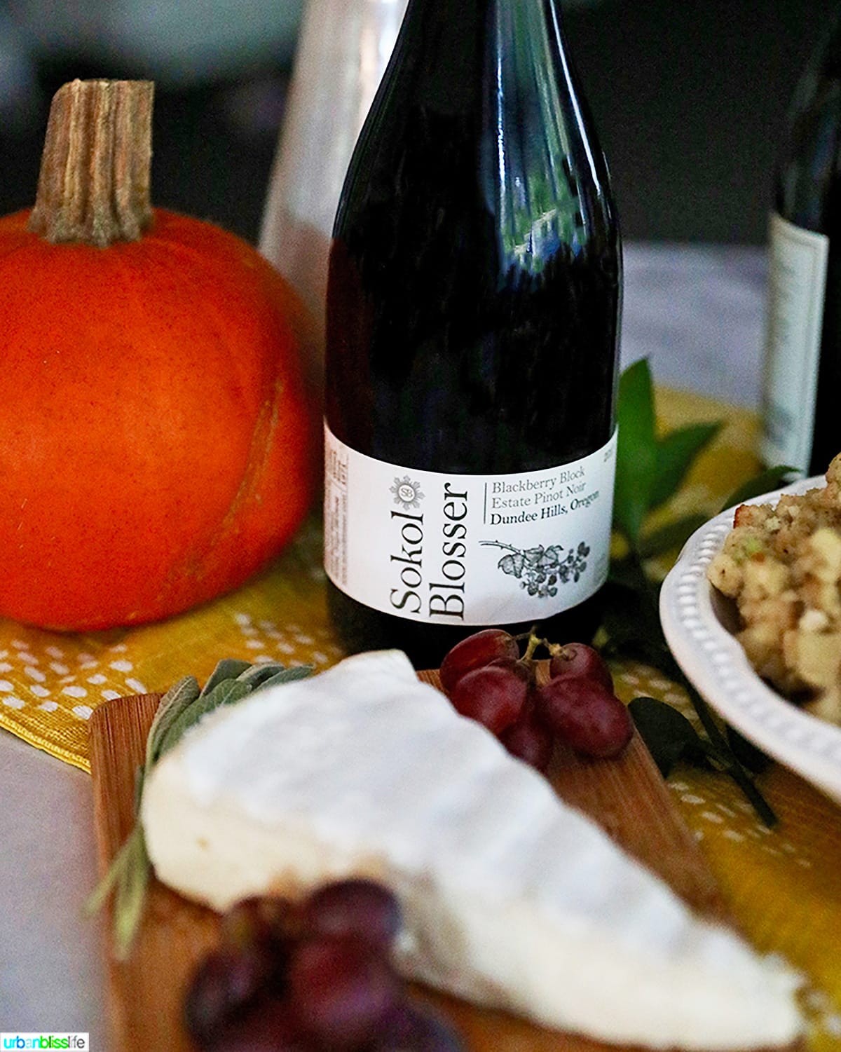 bottle of wine on a table with brie cheese, pumpkin, and stuffing.