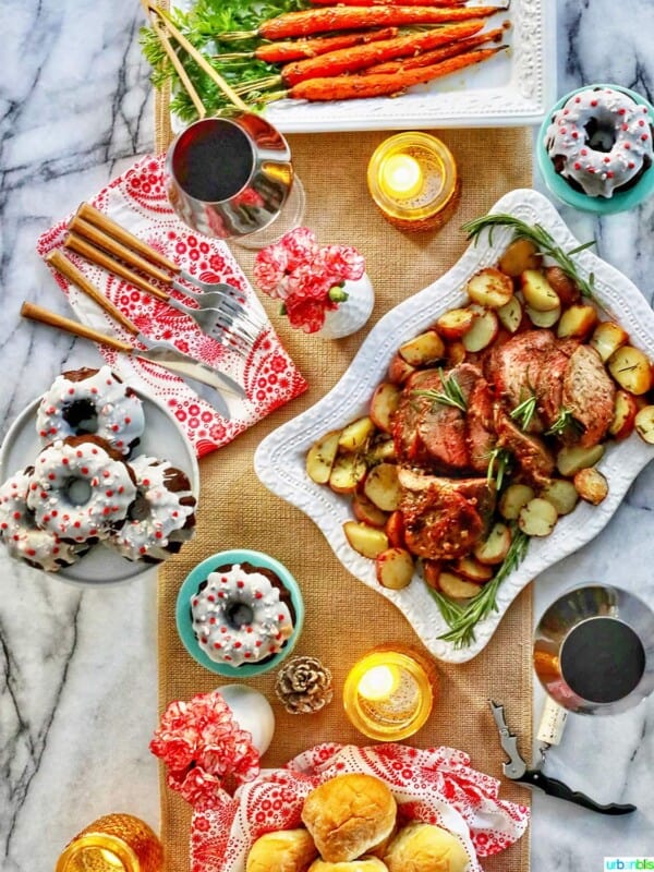 easy holiday meal at home - beef roast, carrots, rolls, glasses of wine, and plates of cake