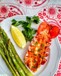 lobster tail with lemon, asparagus, white wine on red and white cloth
