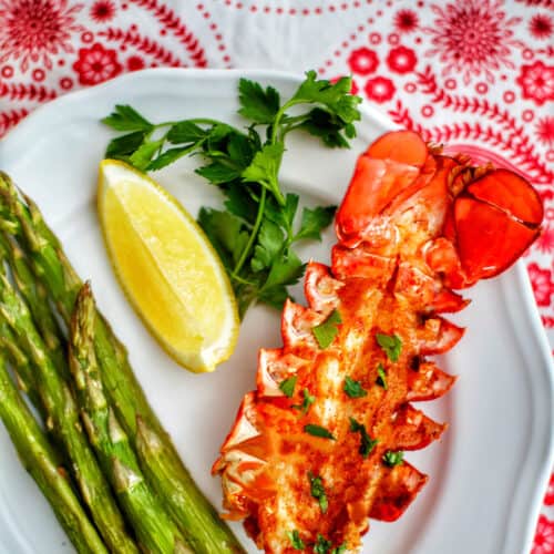 lobster tail with lemon, asparagus, white wine on red and white cloth