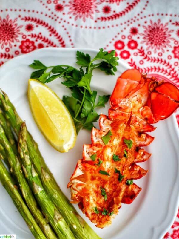 lobster tail with lemon, asparagus, white wine on red and white cloth
