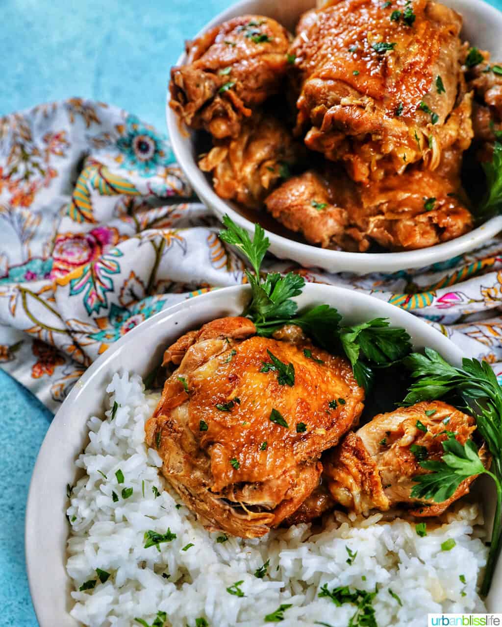 two bowls of Instant Pot Filipino Chicken Adobo and rice, with a colorful floral napkin and forks.