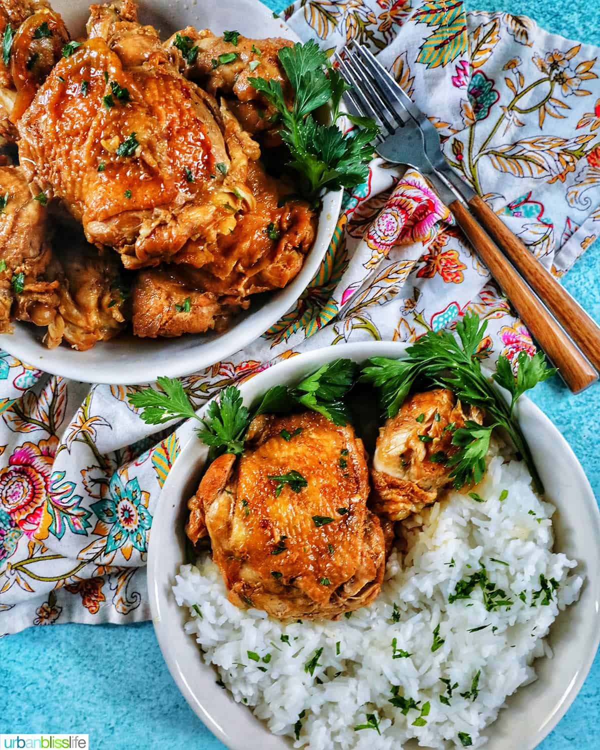two bowls of Instant Pot Filipino Chicken Adobo and rice, with a colorful floral napkin and forks.