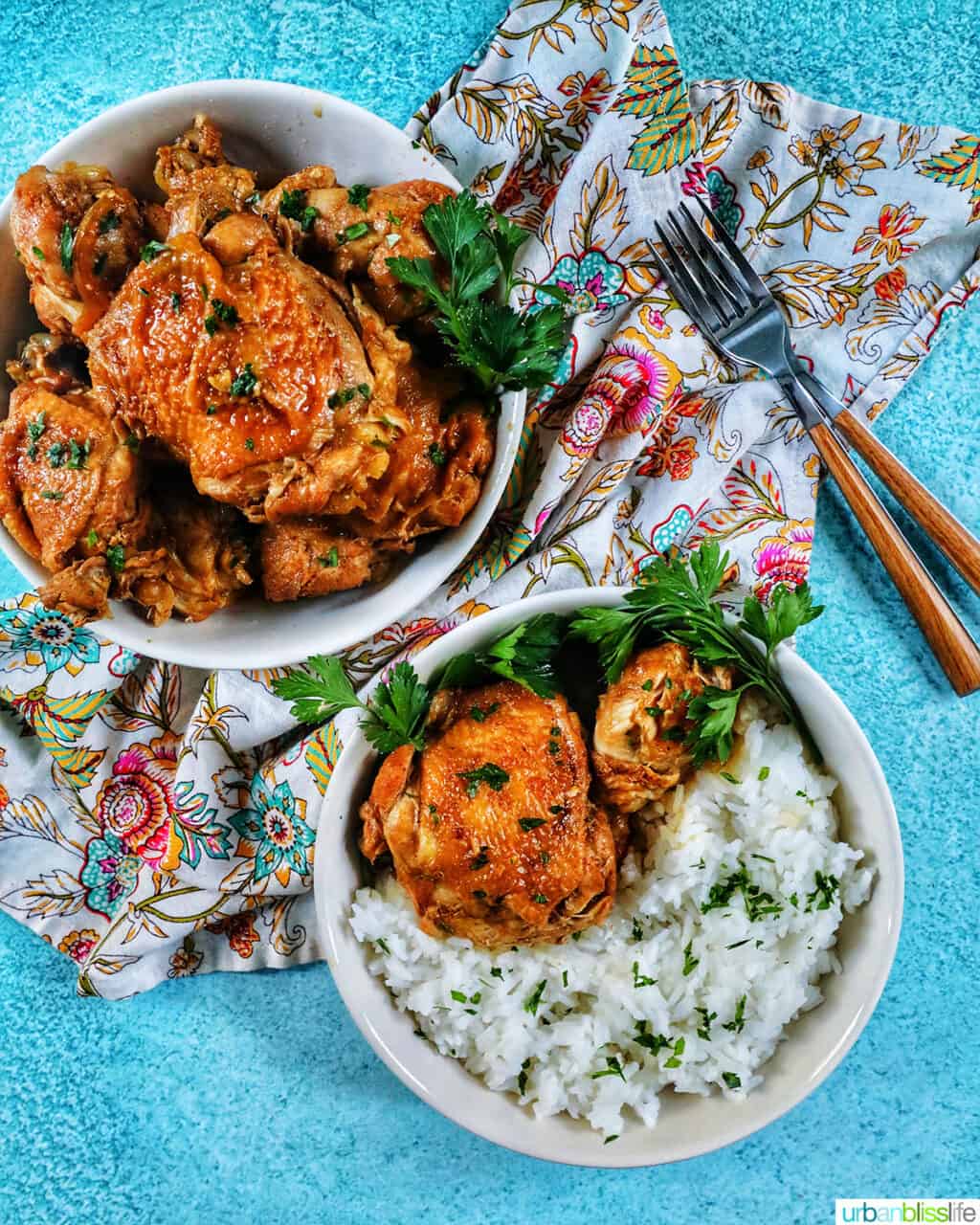 two bowls of Instant Pot Filipino Chicken Adobo and rice, with a colorful floral napkin and forks.