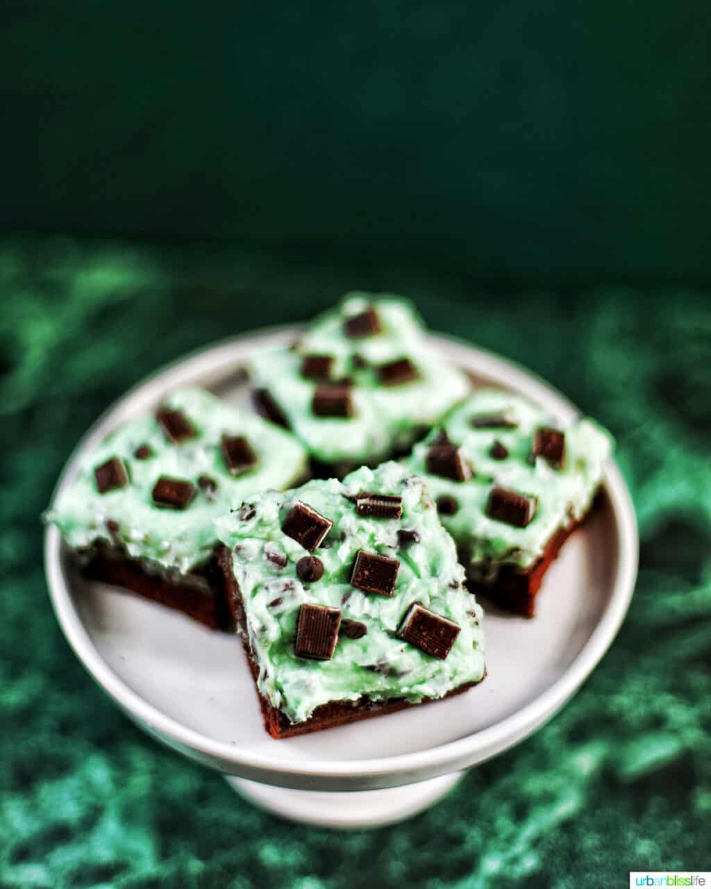 Mint Chocolate Chip Brownies on a cake pedestal on green background