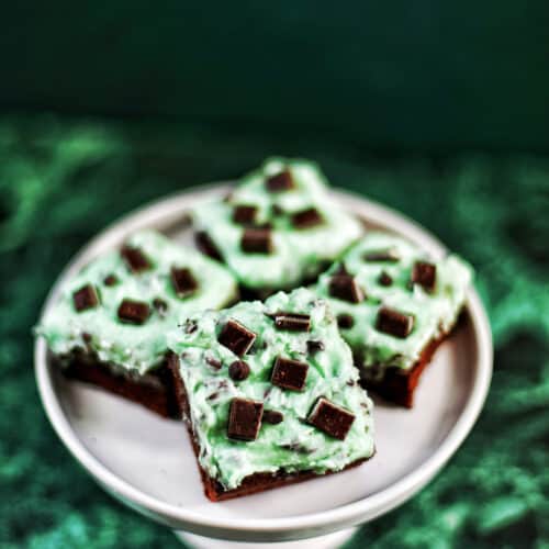 Mint Chocolate Chip Brownies on a cake pedestal on green background