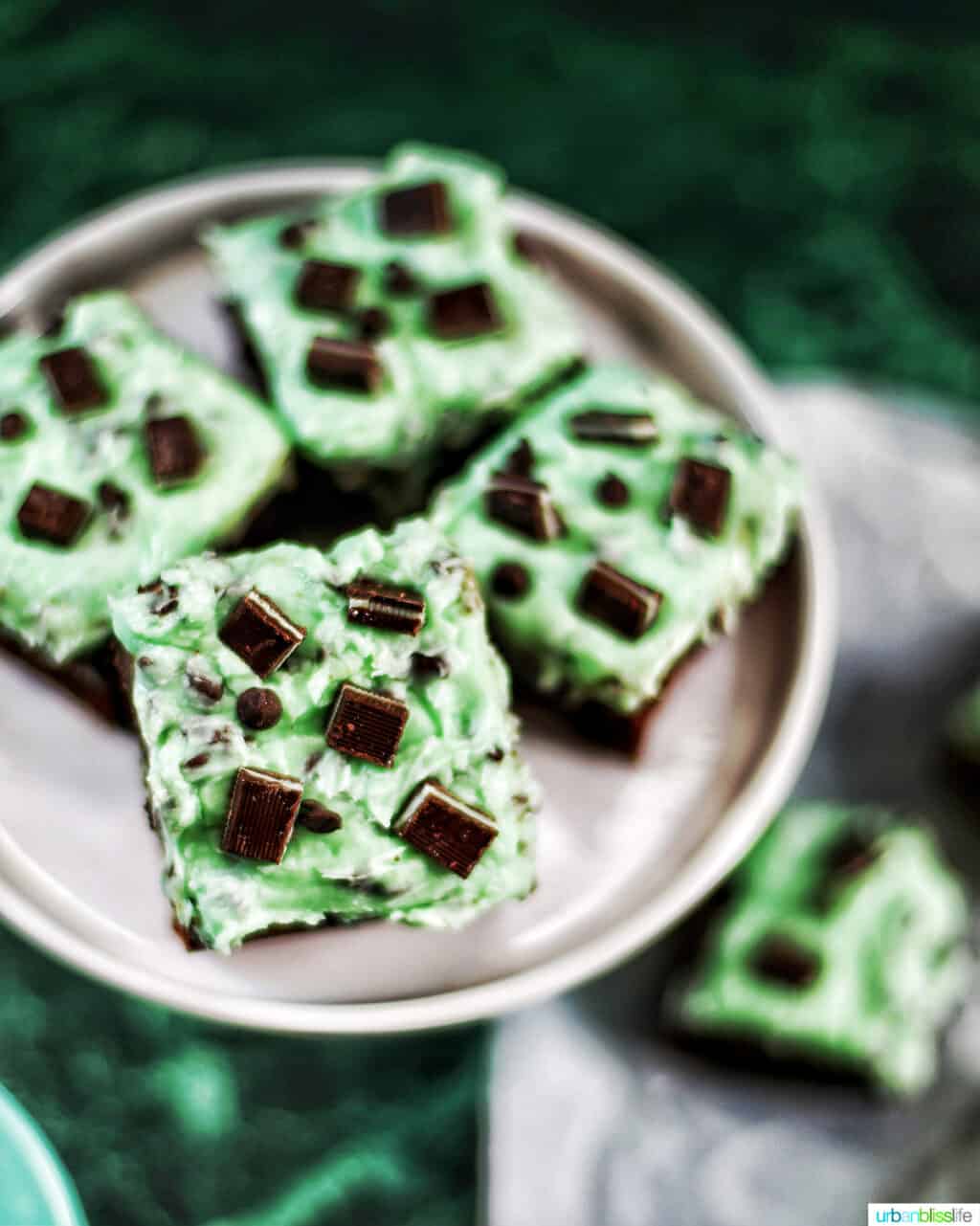 Mint Chocolate Chip Brownies on a cake pedestal on green background