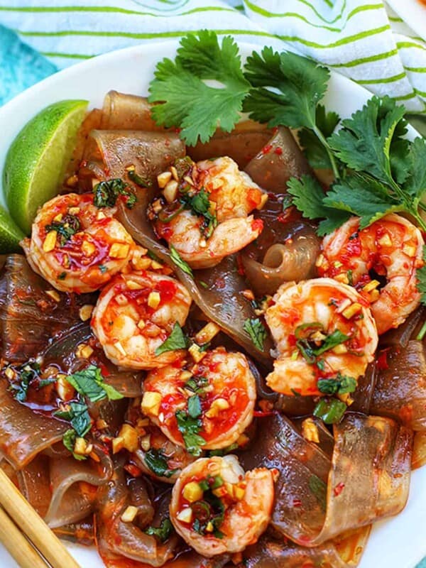 plate of wide glass noodles with shrimp and fresh herbs.