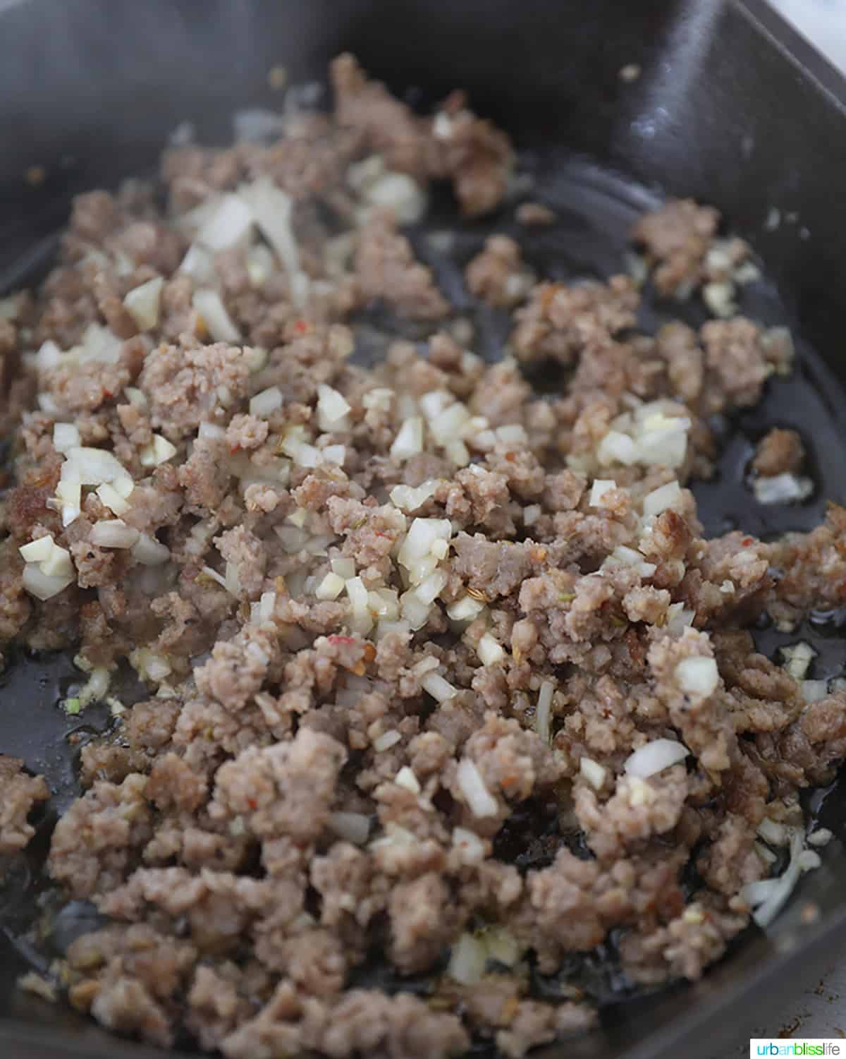 adding sausage to garlic and onions in a pan.