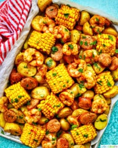 tray of seafood, corn, sausage low country boil with blue background and red and white towel