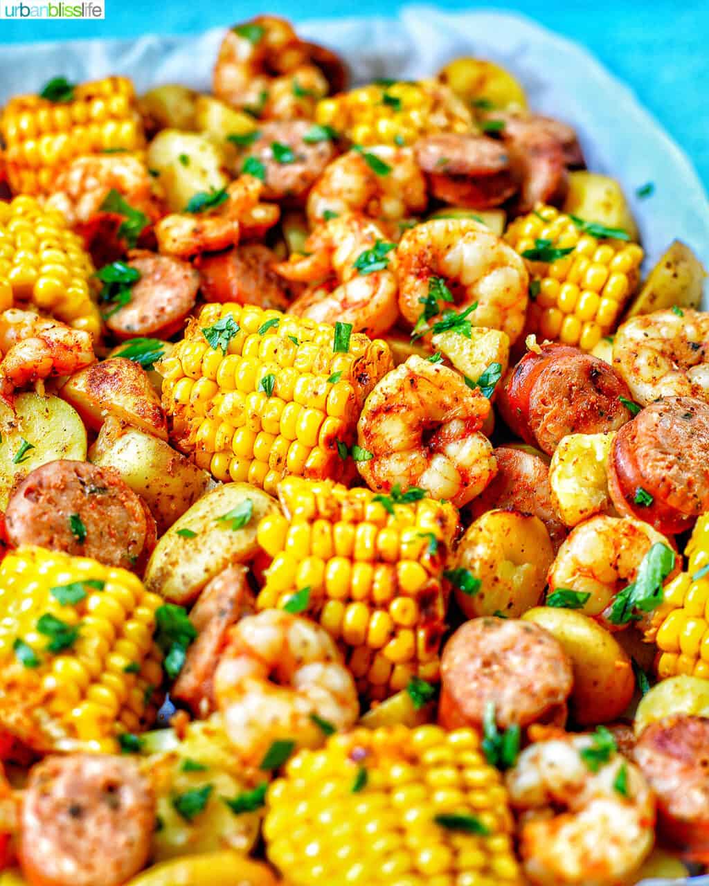 tray of seafood, corn, sausage low country boil with blue background