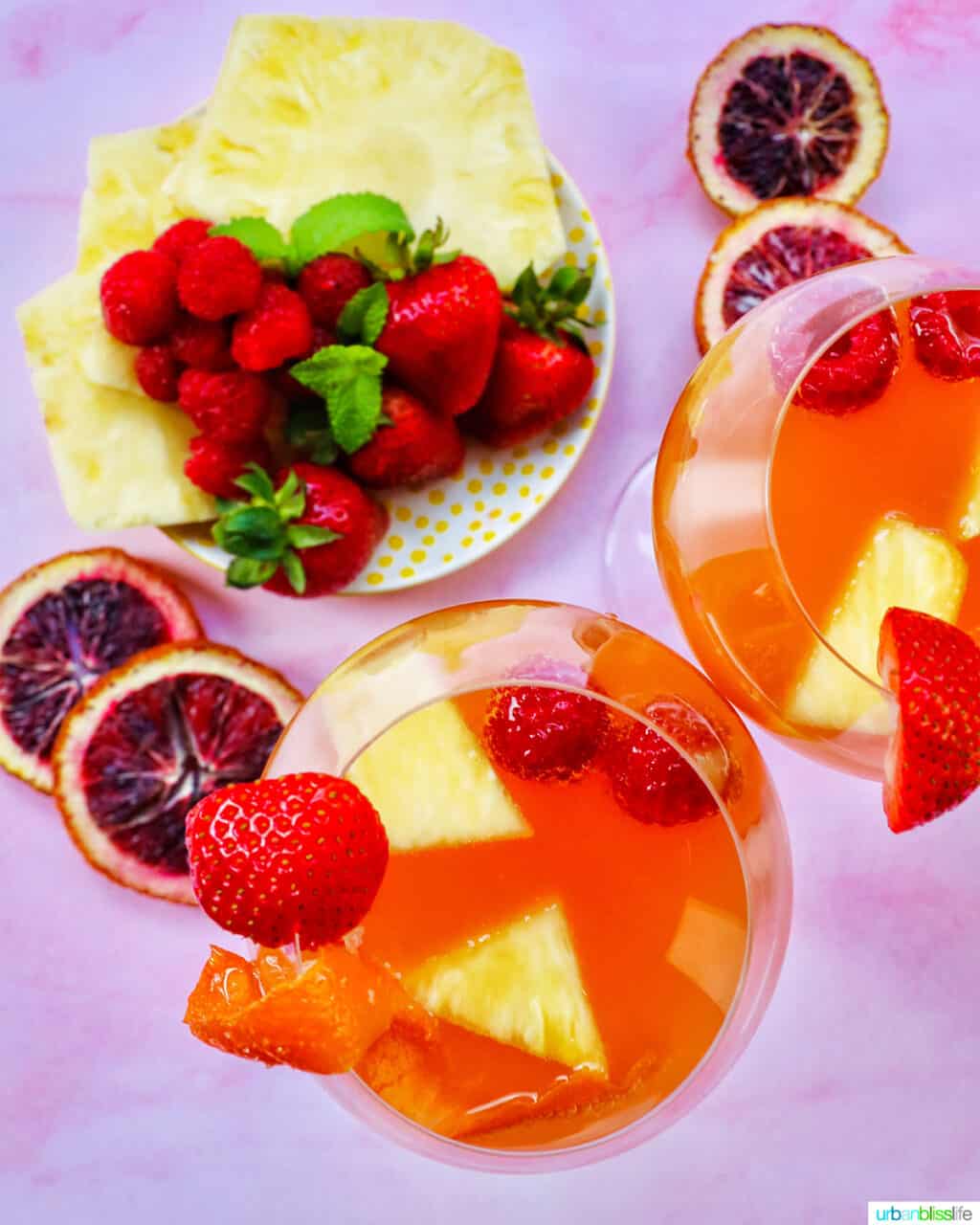 sliced fruit with two glasses of tropical sangria shot from above