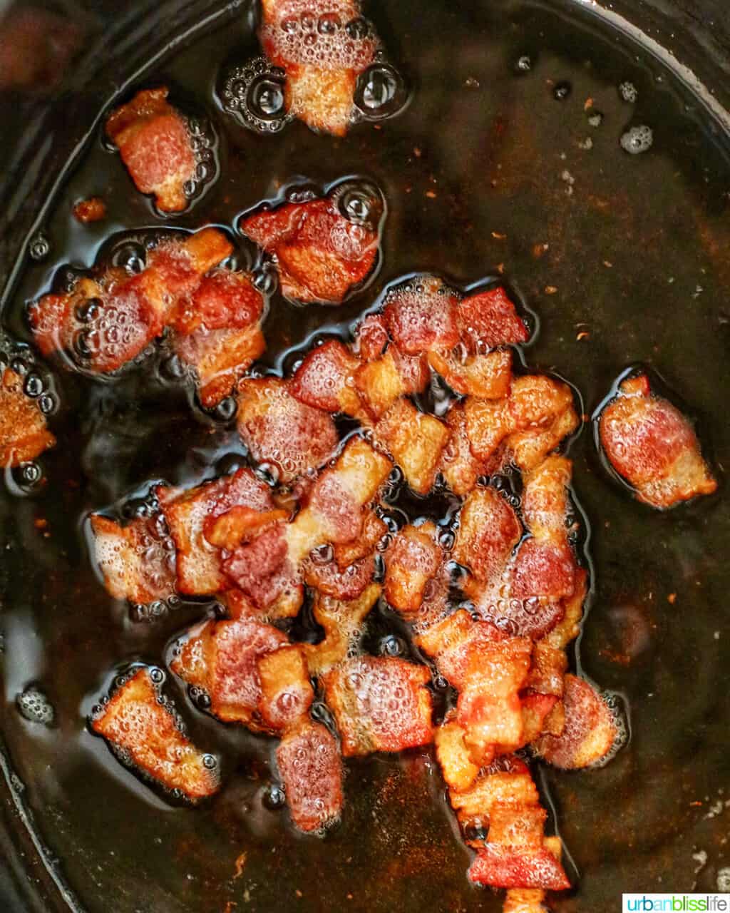 cooked bacon sizzling in Dutch oven