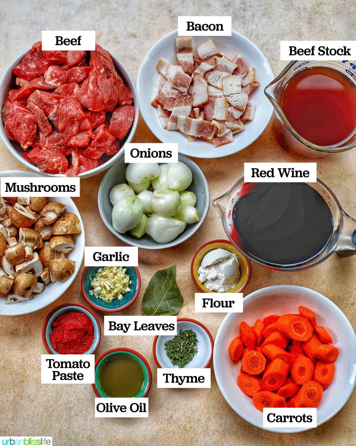 Beef Bourguignon ingredients in bowls on a yellow background.