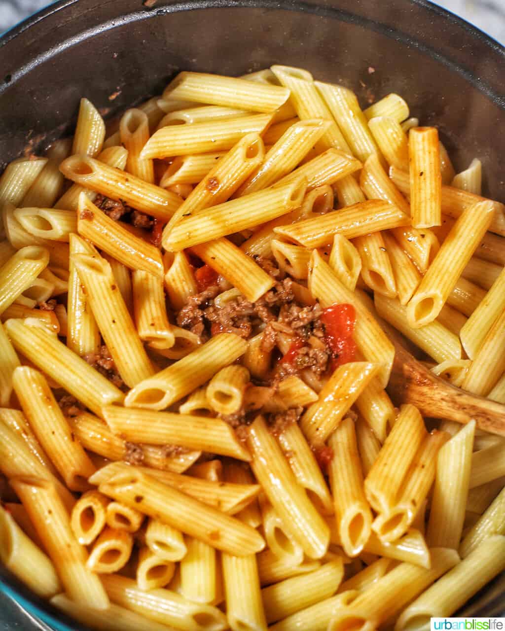 adding pasta to meat sauce
