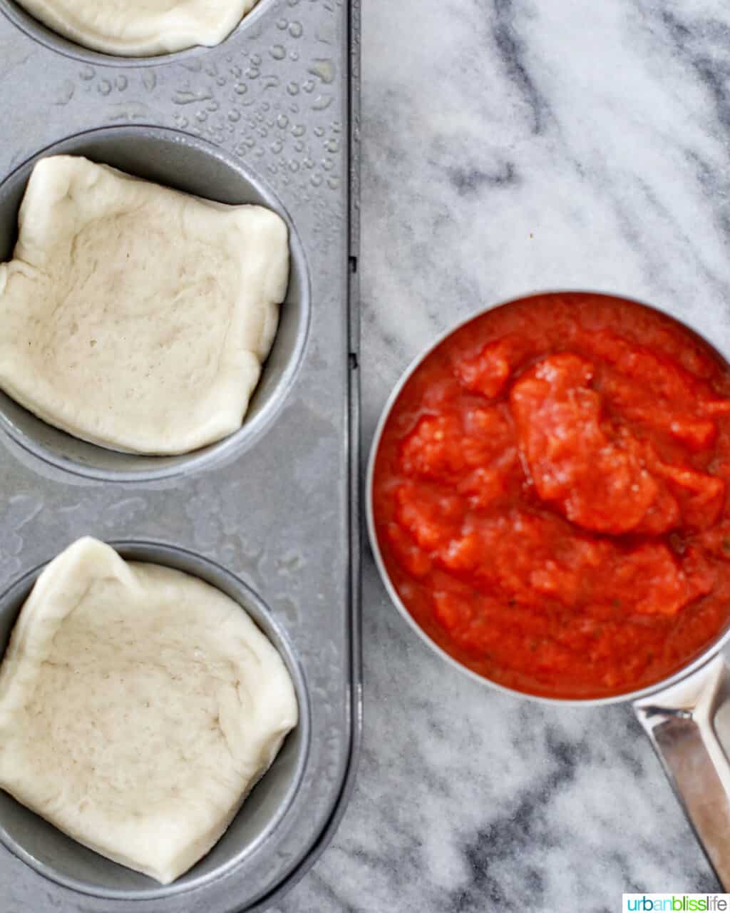 pizza sauce and dough in muffin tins
