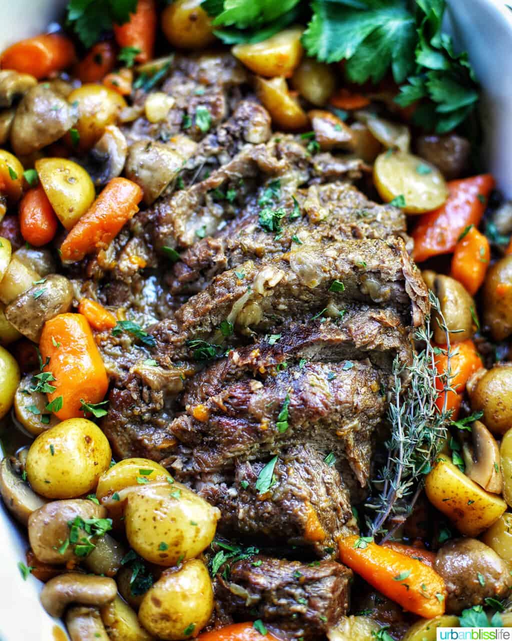 close up of dutch oven pot roast with vegetables in a large white serving platter