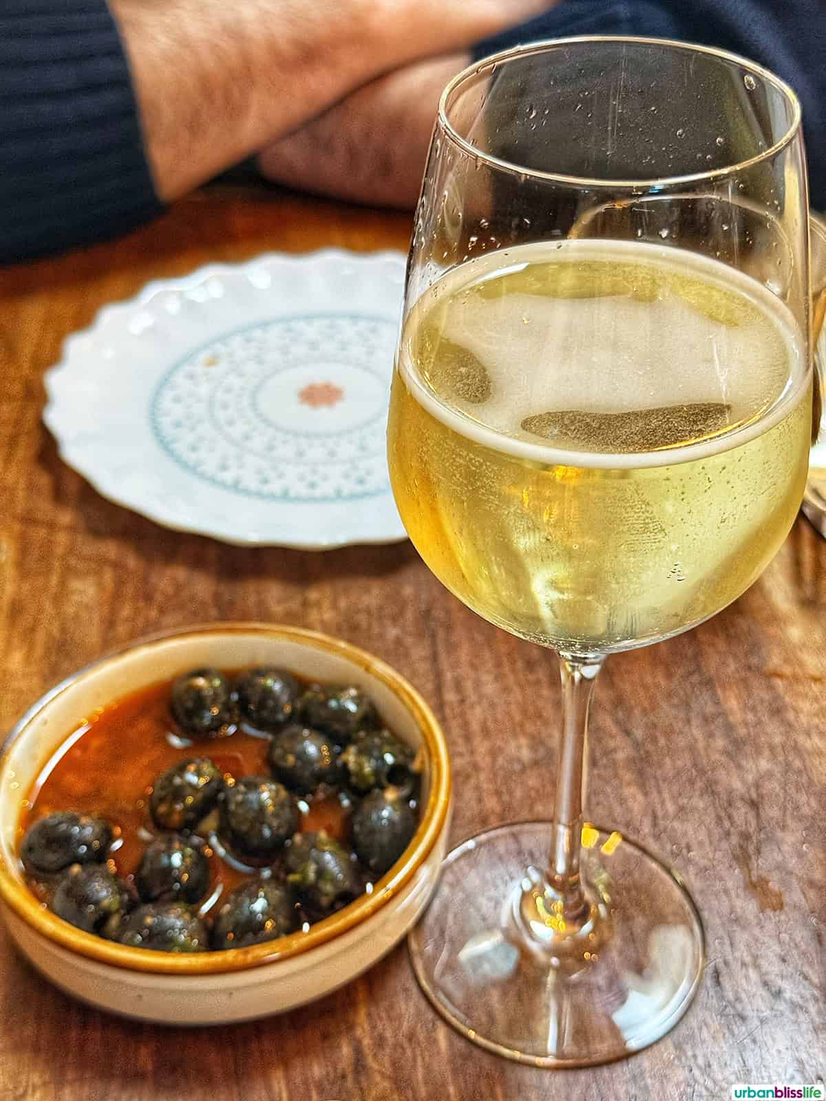 glass of white wine with marinated olives in Urdaneta restaurant in Portland, Oregon.