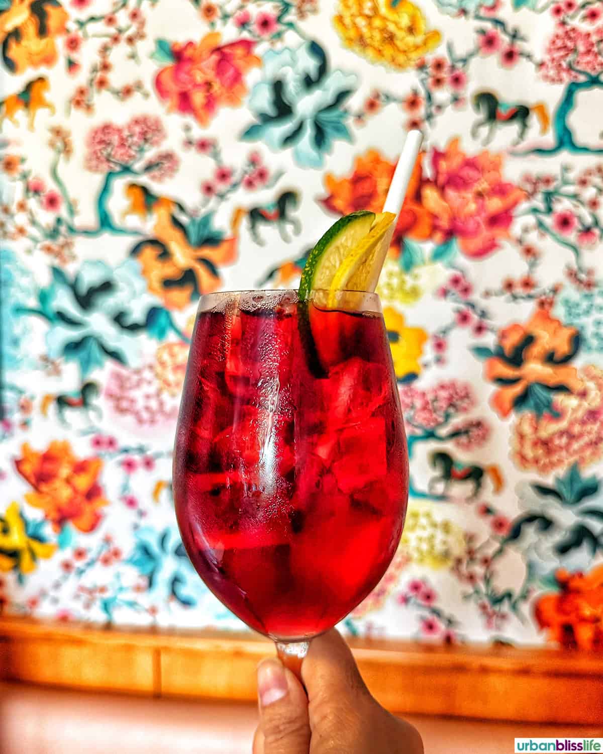 glass of tinto de verano cocktail in front of colorful wallpaper at Vya PDX restaurant.