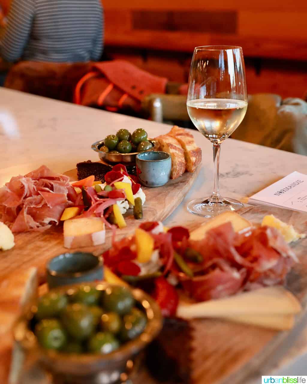 glass of white wine next to charcuterie boards  at normandie restaurant in Portland, Oregon.