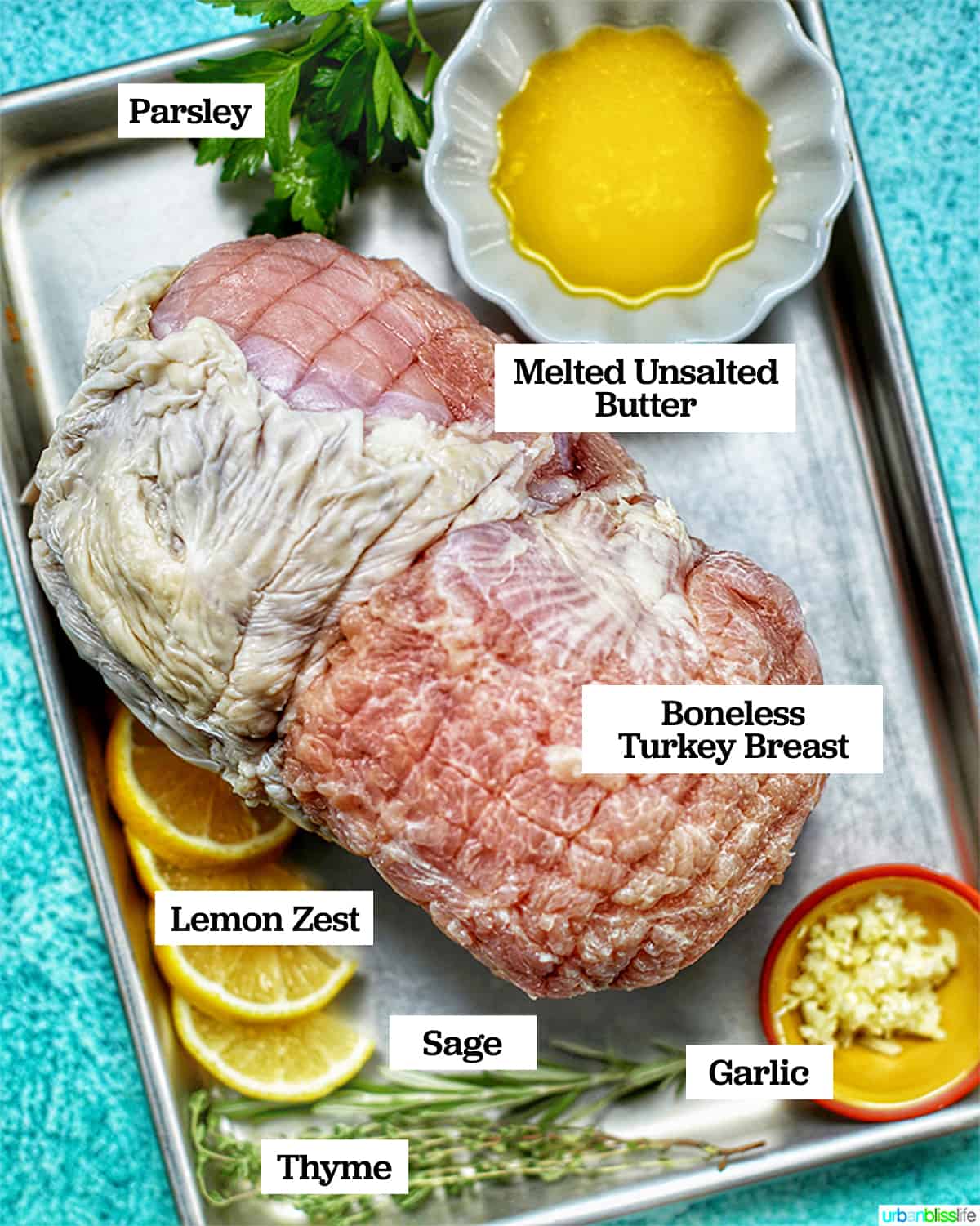 turkey breast ingredients on baking sheet against blue backdrop.