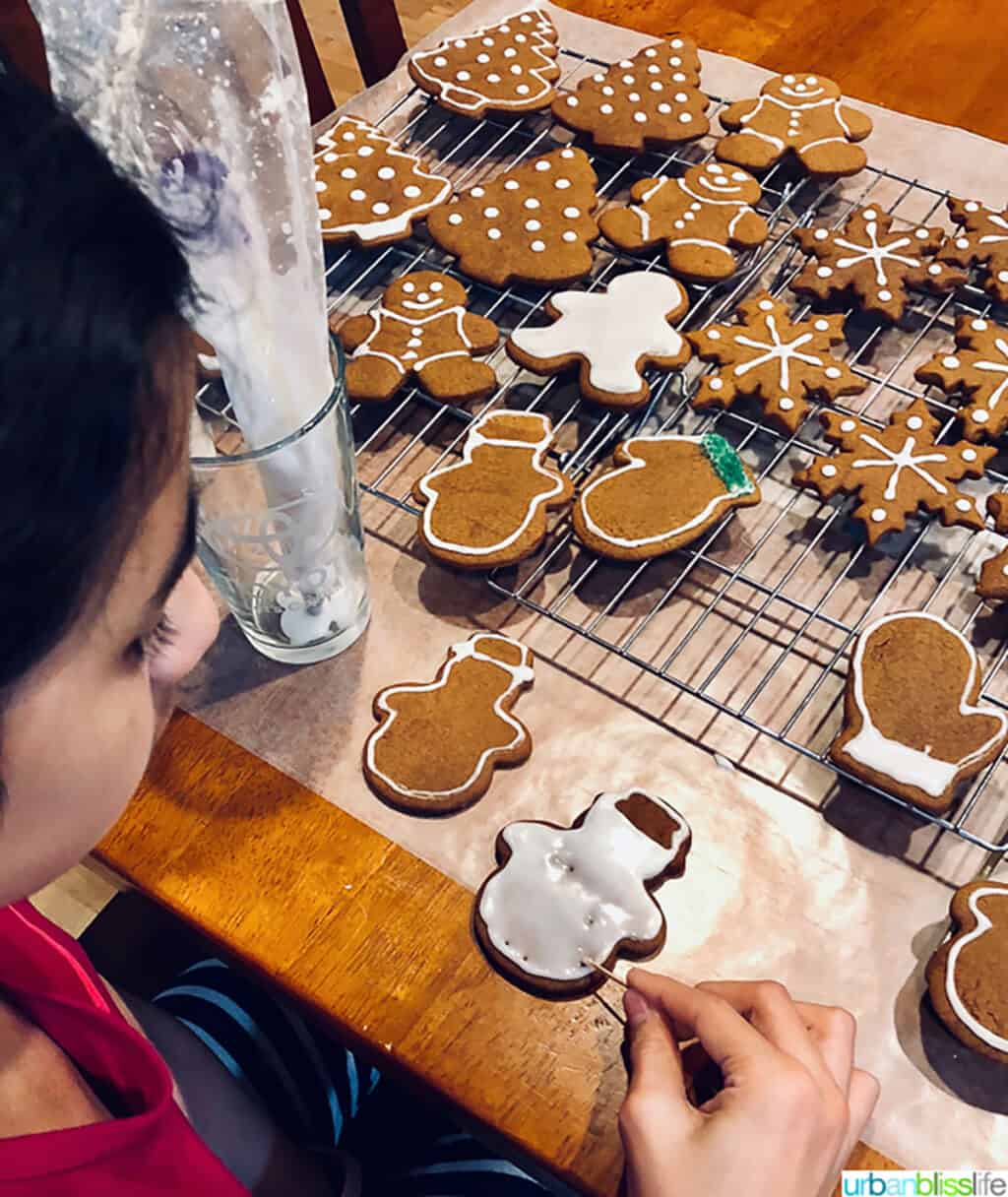 Girl decorating Soft Gingerbread Cookies in snowman shapes