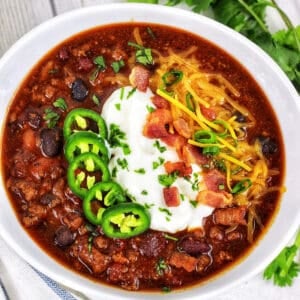 bowl of Instant Pot Turkey Chili with jalapenos, sour cream, bacon, and cheese.