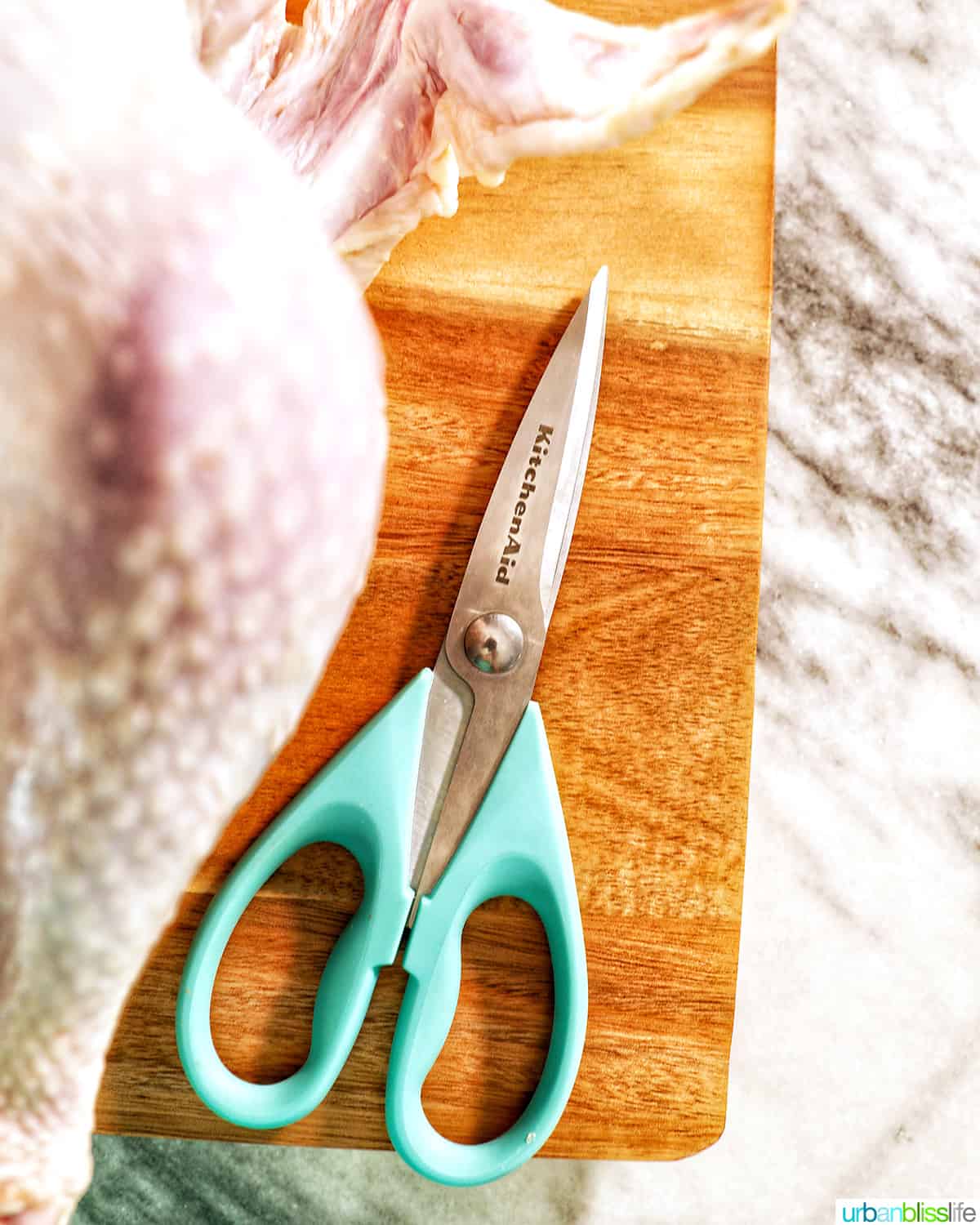 KitchenAid kitchen shears to spatchcock a turkey on a cutting board.