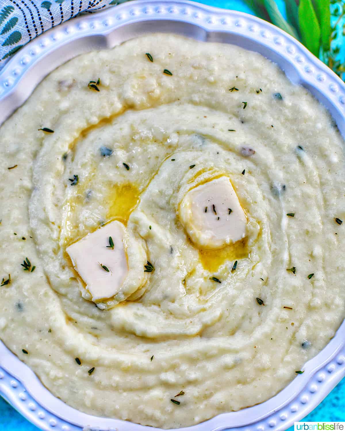 Instant Pot Garlic Mashed Potatoes in a bowl with pats of melting butter and herbs.