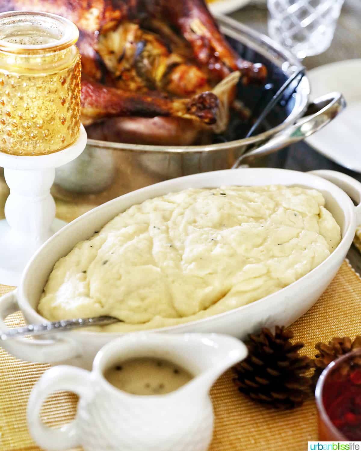 garlic mashed potatoes on Thanksgiving table in a serving bowl with turkey in the background.