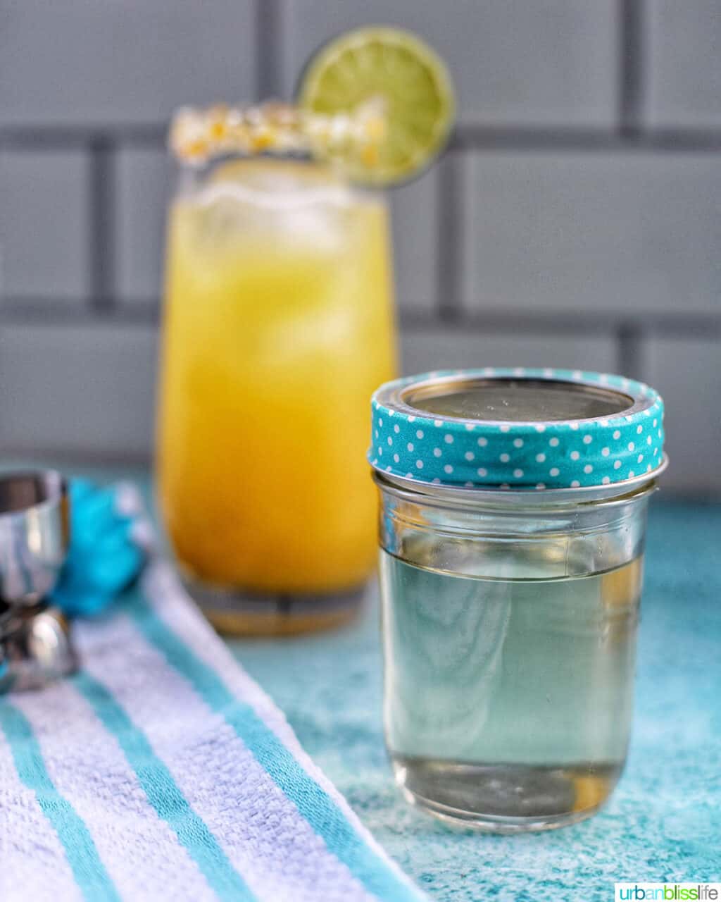 jar of simple syrup with cocktail in background