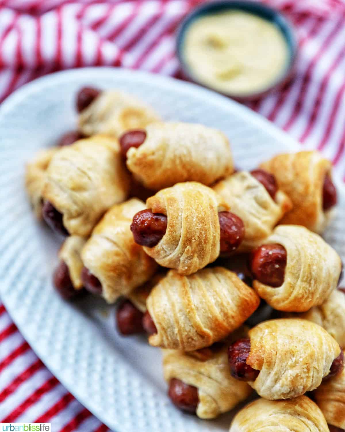 dozens of Air Fryer Pigs in a Blanket stacked on top of a white plate.