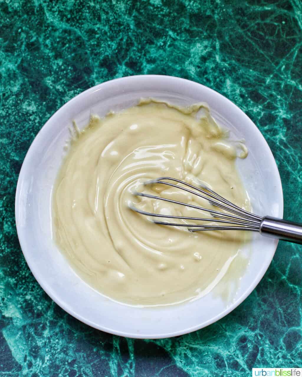 melted white chocolate in a bowl with a small whisk