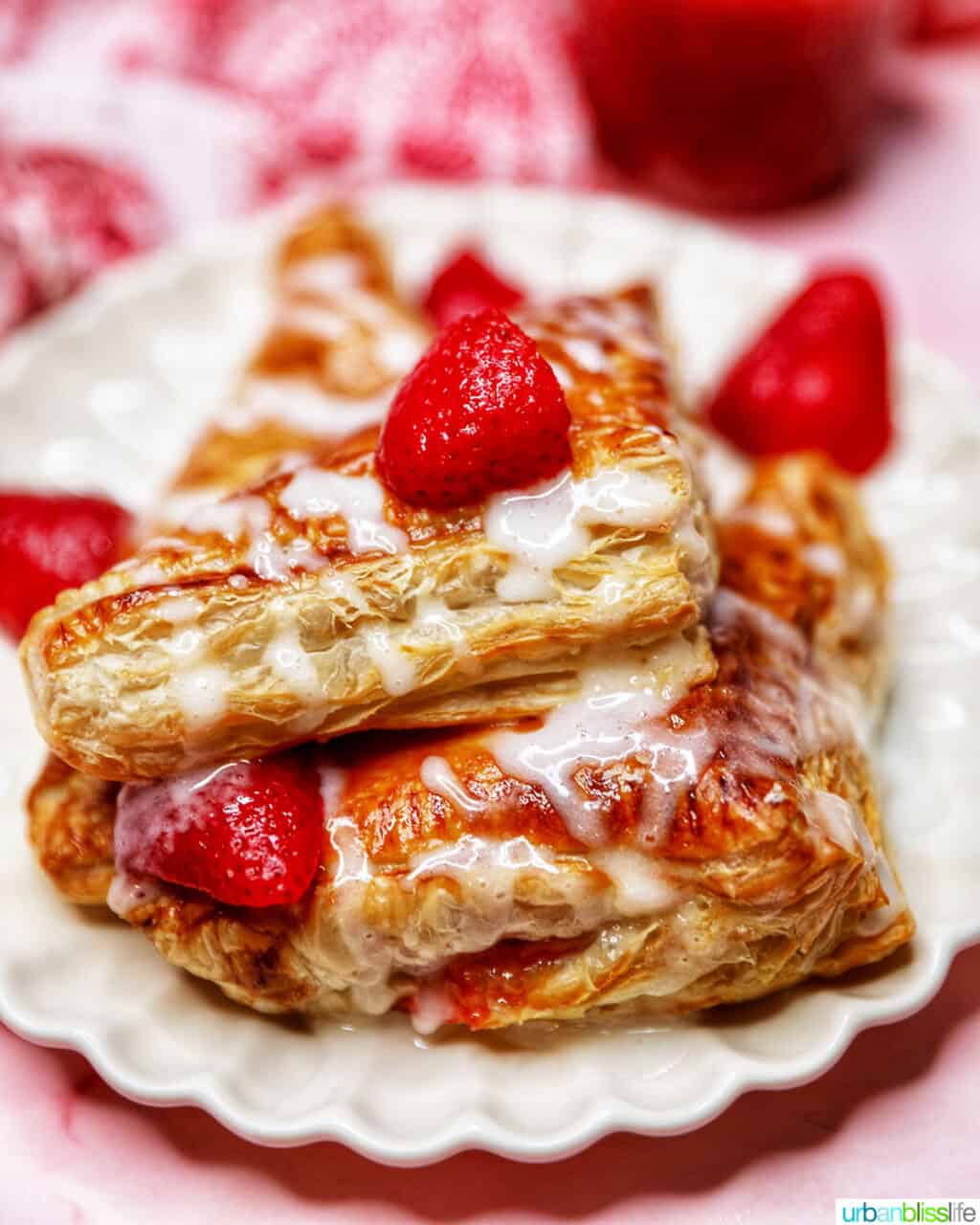 iced air fryer strawberry turnovers stacked on a plate with strawberries