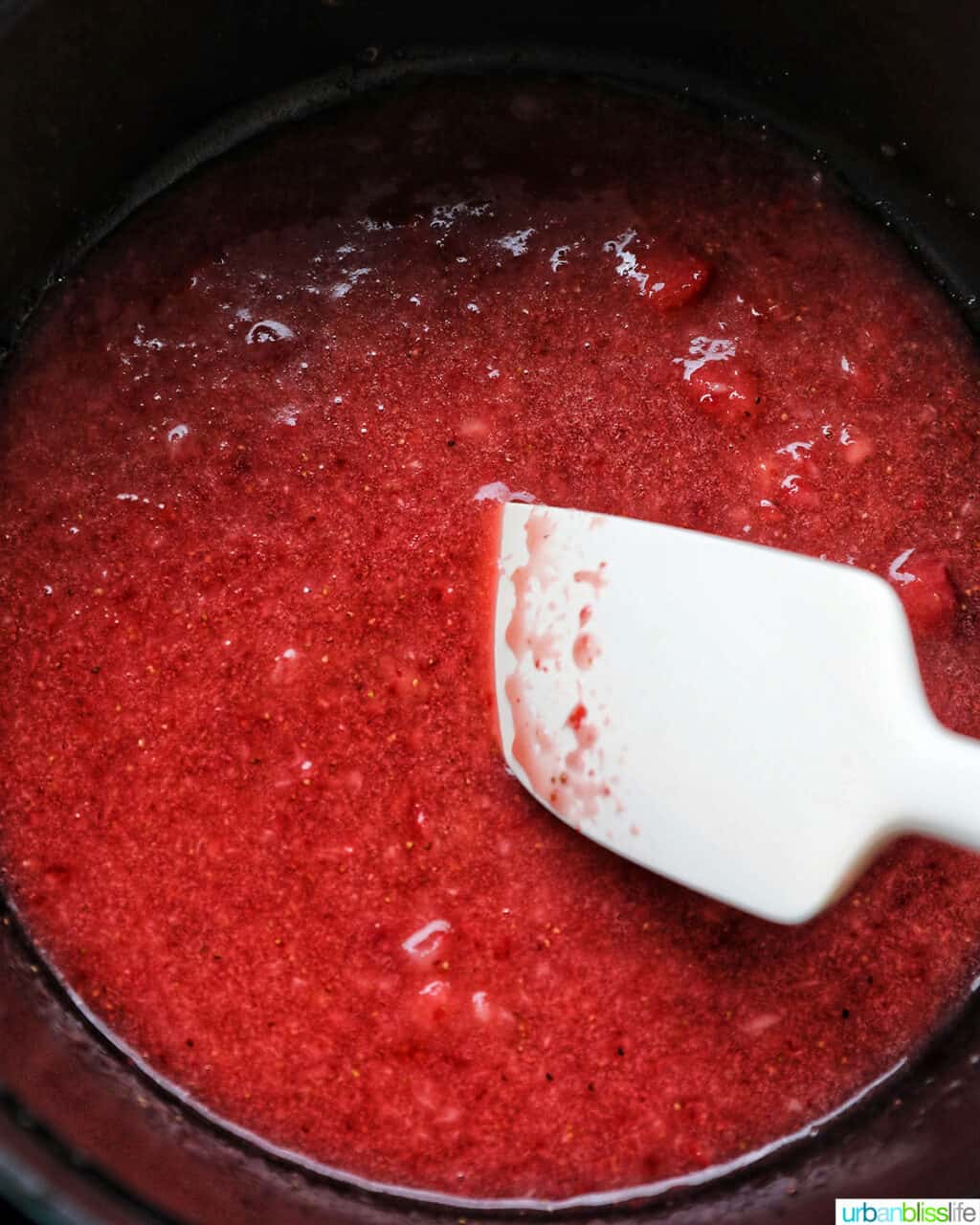 spatula stirring pureed strawberries in pot