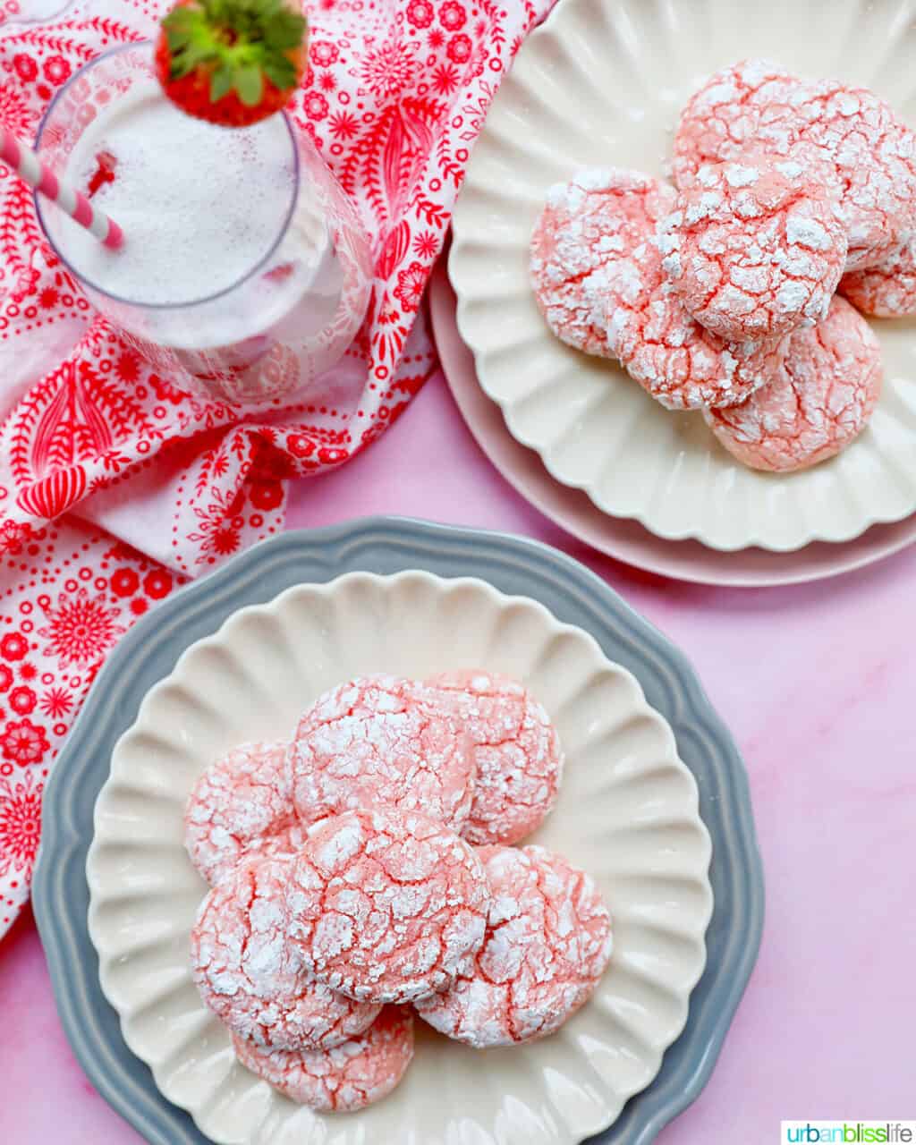 two plates with stacks of strawberry crinkle cookies and glass of strawberry milk