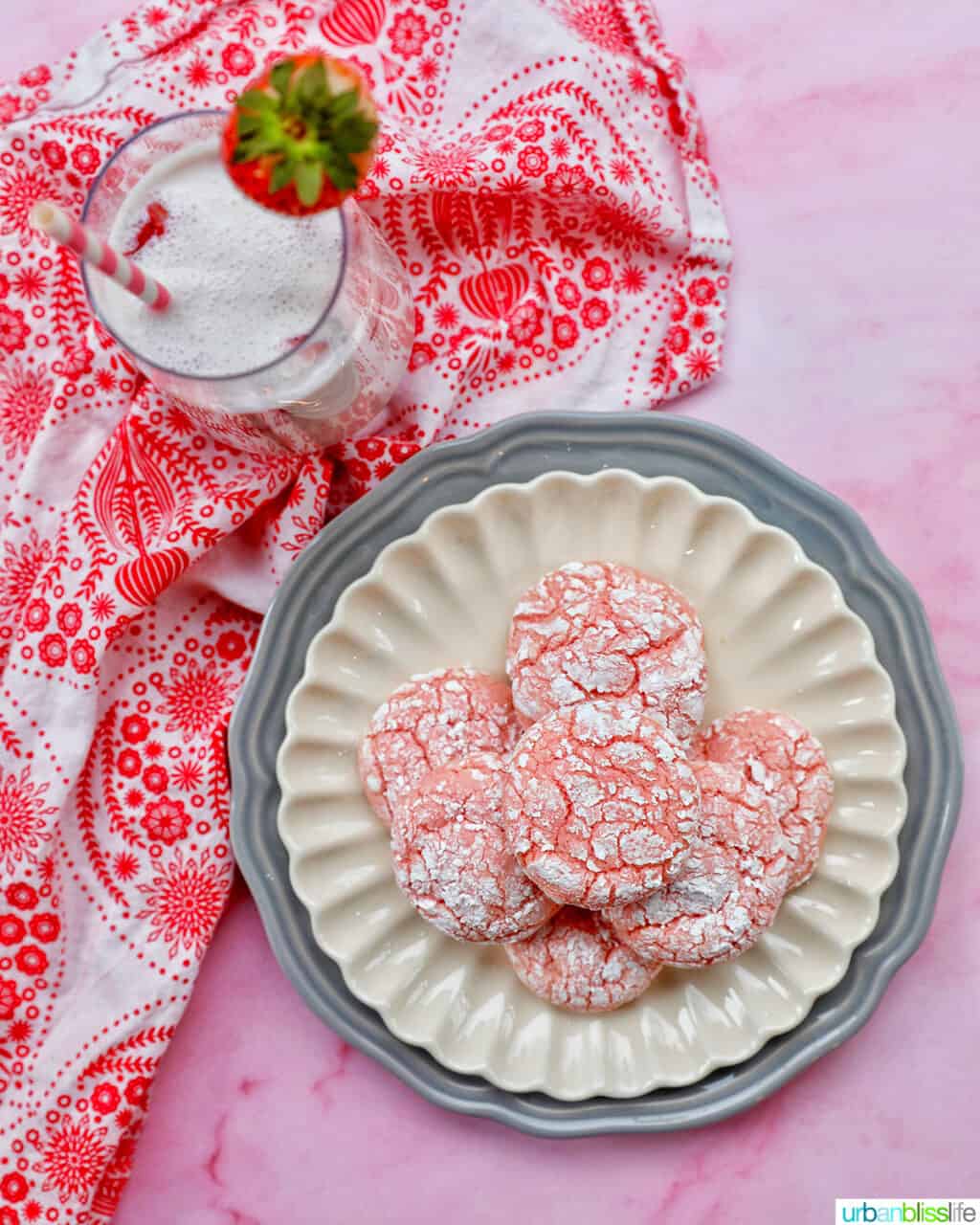 plate of baked strawberry crinkle cookies with glass of strawberry milk